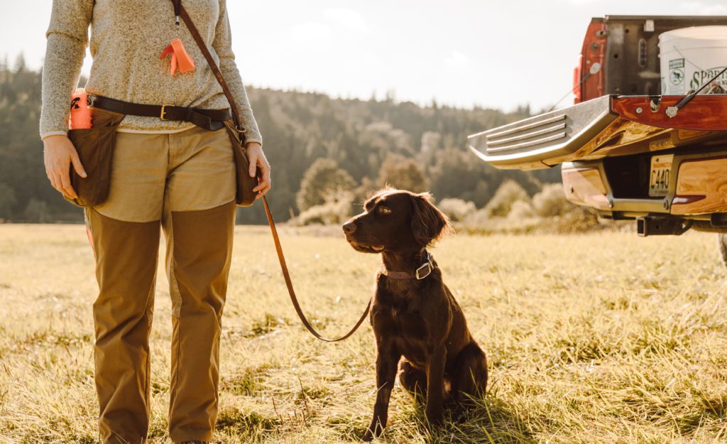 A trainer stands with her dog.
